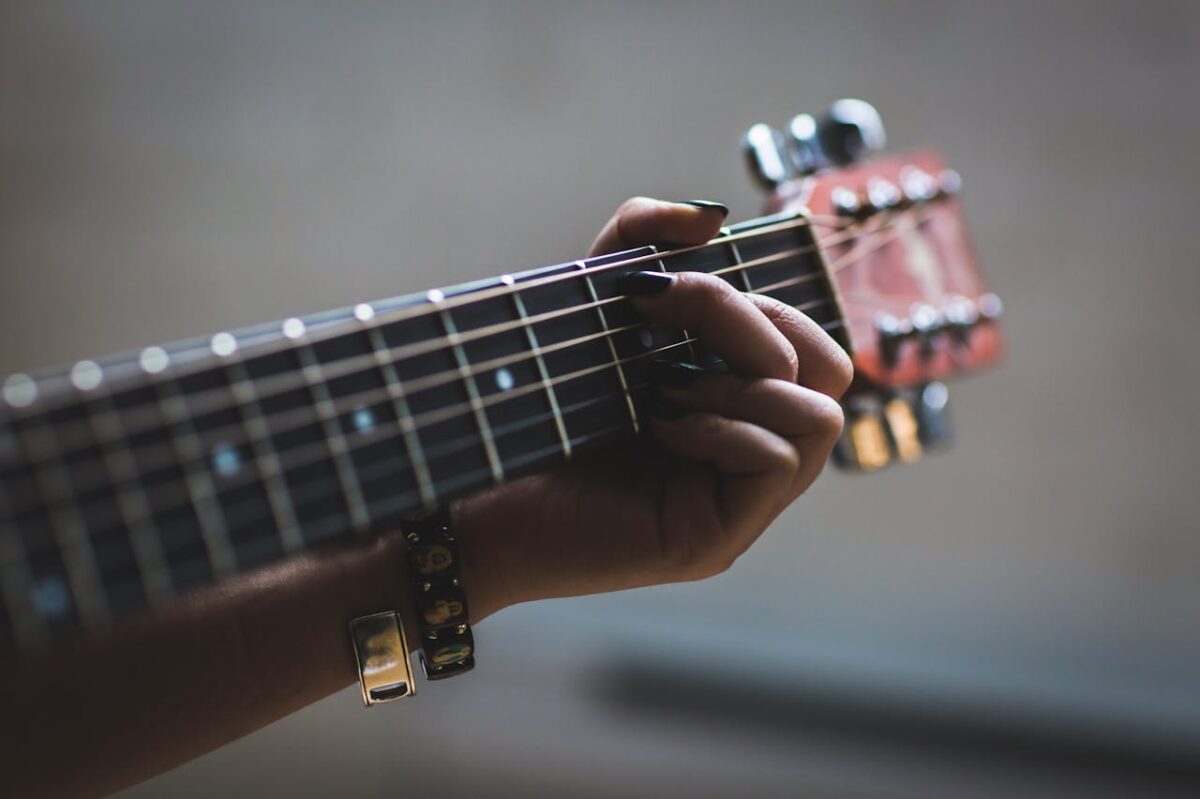 A musician's hand skillfully playing an acoustic guitar, focusing on the fretboard and strings.