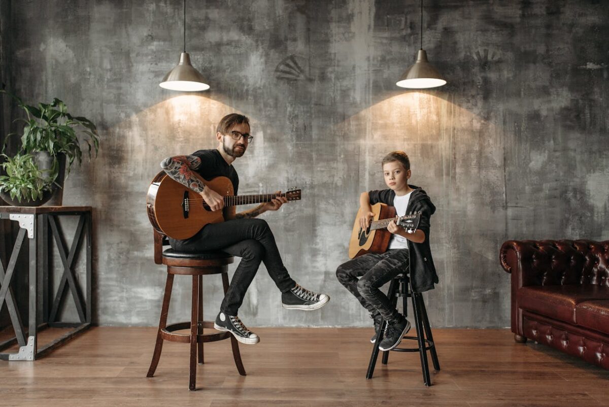 A father and son enjoying a guitar lesson together in a stylish loft setting.